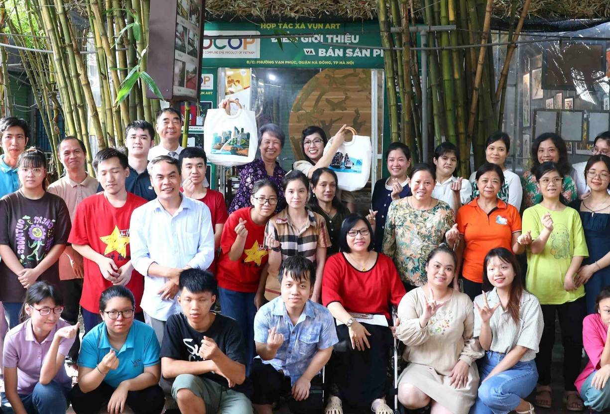 The two spouses of the top Vietnamese and Singaporean officials pose for a group photo with disabled artisans at the Vun Art Cooperative in Hanoi. Photo: Vietnam News Agency