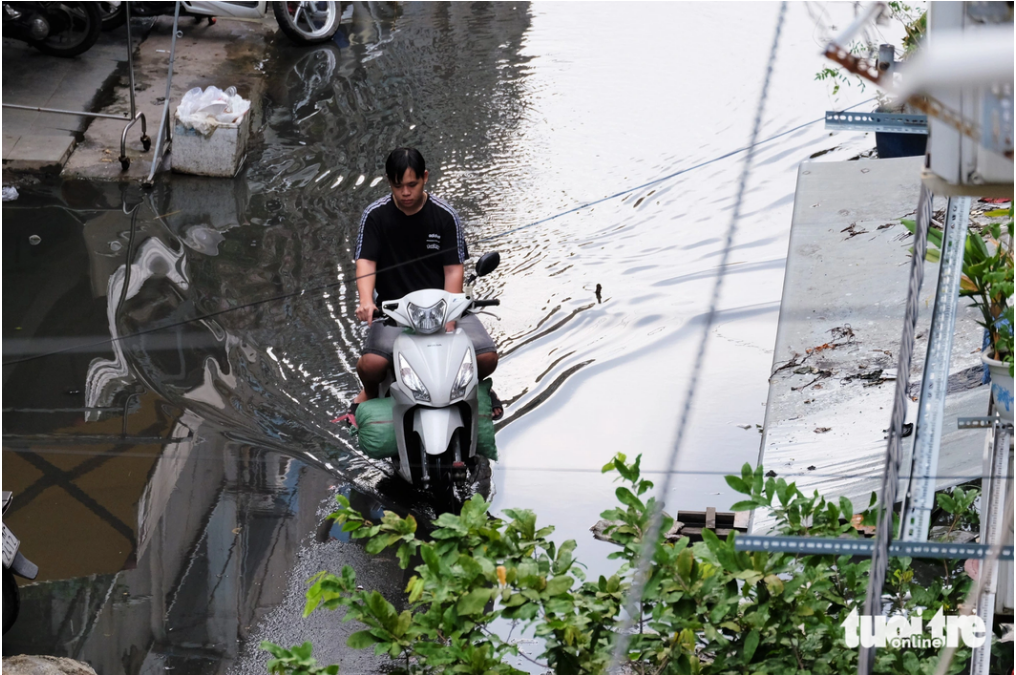A man rides a motorbike on a route flooded with drainage water in An Quang apartment building. Photo: Phuong Nhi / Tuoi Tre
