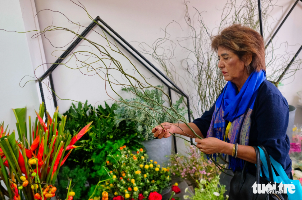 A foreigner shows her curiosity about flowers and materials for flower arranging at the 37th World Flower Council Summit in Da Lat City. Photo: Mai Vinh / Tuoi Tre