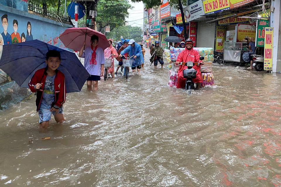 People make their way through a flooded street after heavy rains in Hanoi, Vietnam September 28, 2023. Photo: Reuters