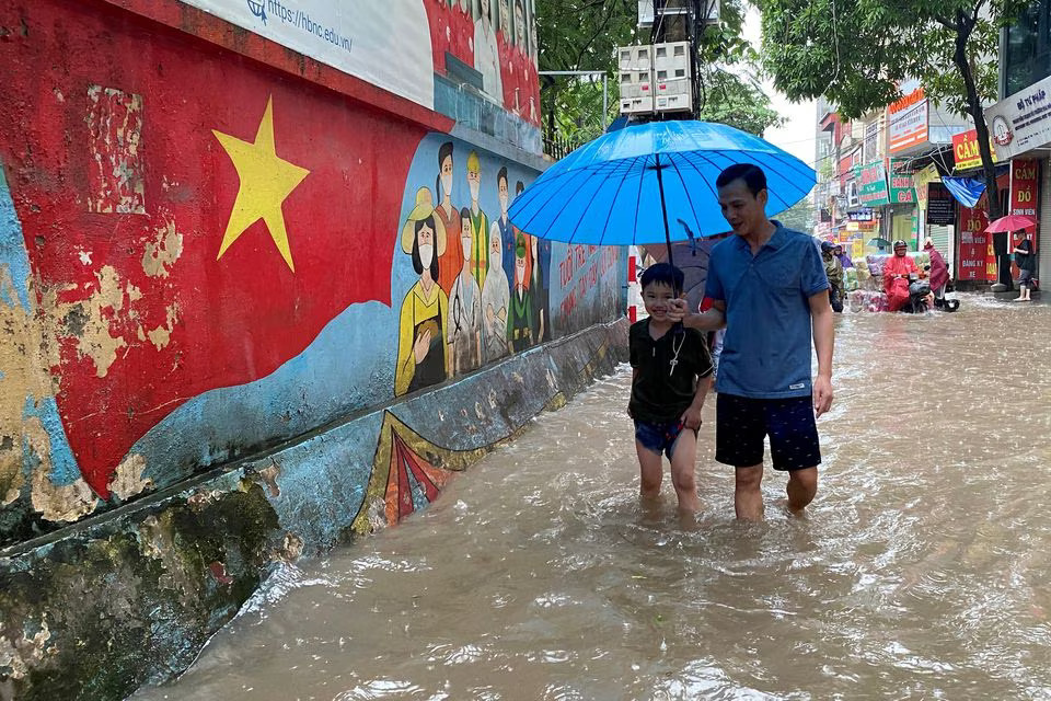 A man and a boy walk through a flooded street after heavy rains in Hanoi, Vietnam September 28, 2023. Photo: Reuters