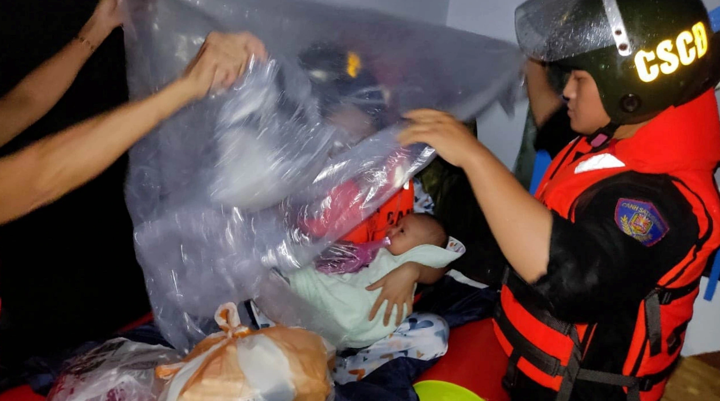 Rescue workers transport a baby and a woman on a boat to a safer shelter as heavy rain floods many parts of Da Nang City, central Vietnam. Photo: H.B. / Tuoi Tre