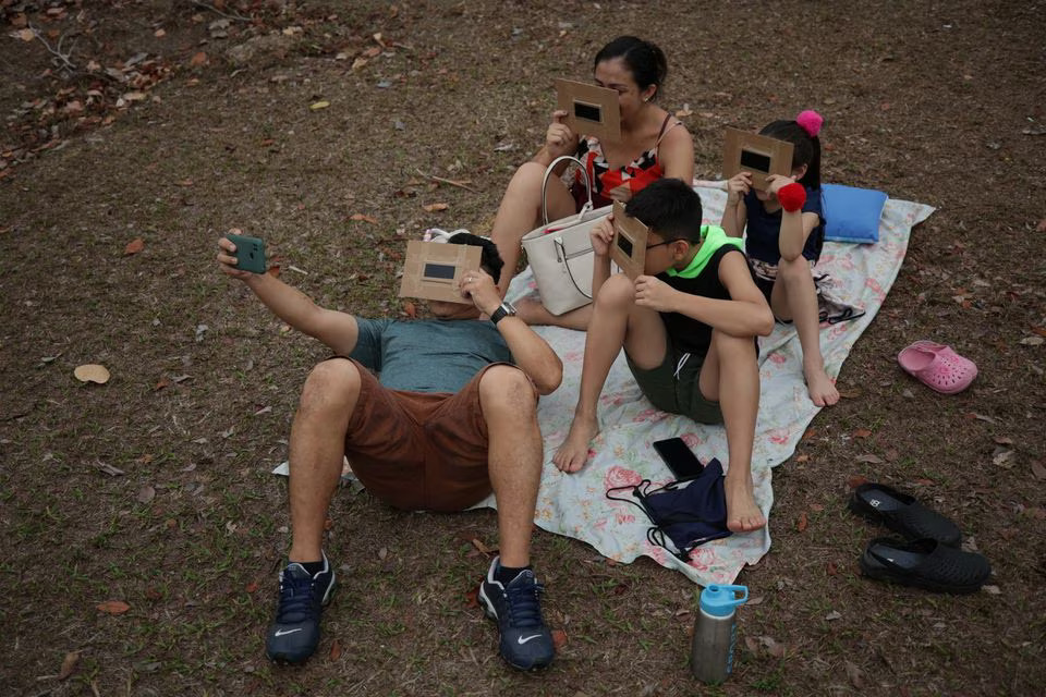 A family gathers to watch the solar eclipse at UFAM university in Manaus, Brazil, October 14. Photo: Reuters