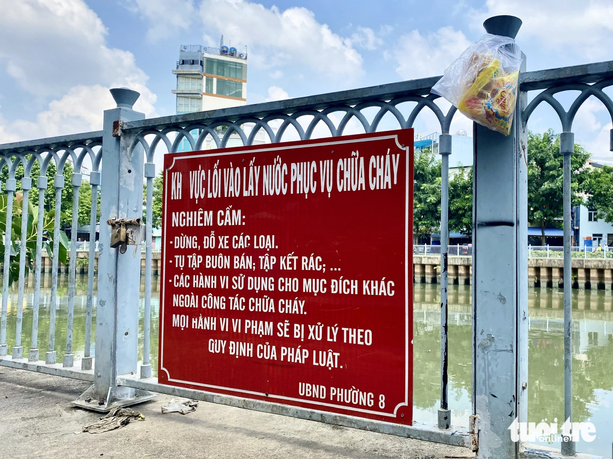 A bag of trash is hung next to a sign banning parking, gatherings, and littering along Nhieu Loc - Thi Nghe Canal. Photo: Tien Quoc / Tuoi Tre