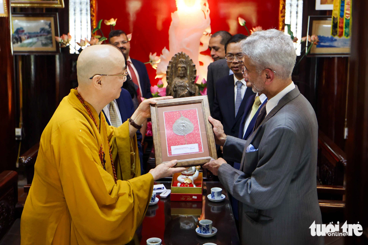 The Venerable Thich Thanh Nha, abbot of the pagoda, introduces the Buddhist temple’s establishment and development to the two top officials. He gives two Bodhi leaves to the two ministers. The Bodhi tree is considered a sacred symbol of Buddhism. Photo: Nguyen Khanh / Tuoi Tre