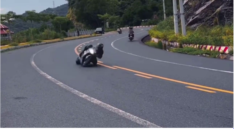 A video screenshot shows a person taking a bend with his knee touching the road surface.