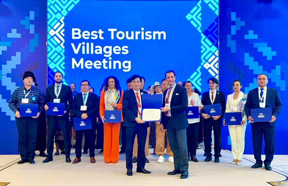 A representative of Tan Hoa Commune (L) receives a certificate of the best tourism village by the UNWTO on October 19, 2023. Photo: D.L. / Tuoi Tre